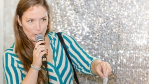 Foto von Svenja Hirsch auf der Frankfurter Buchmesse, sie hält ein Mikrofon in der Hand und moderiert eine Lesung an.